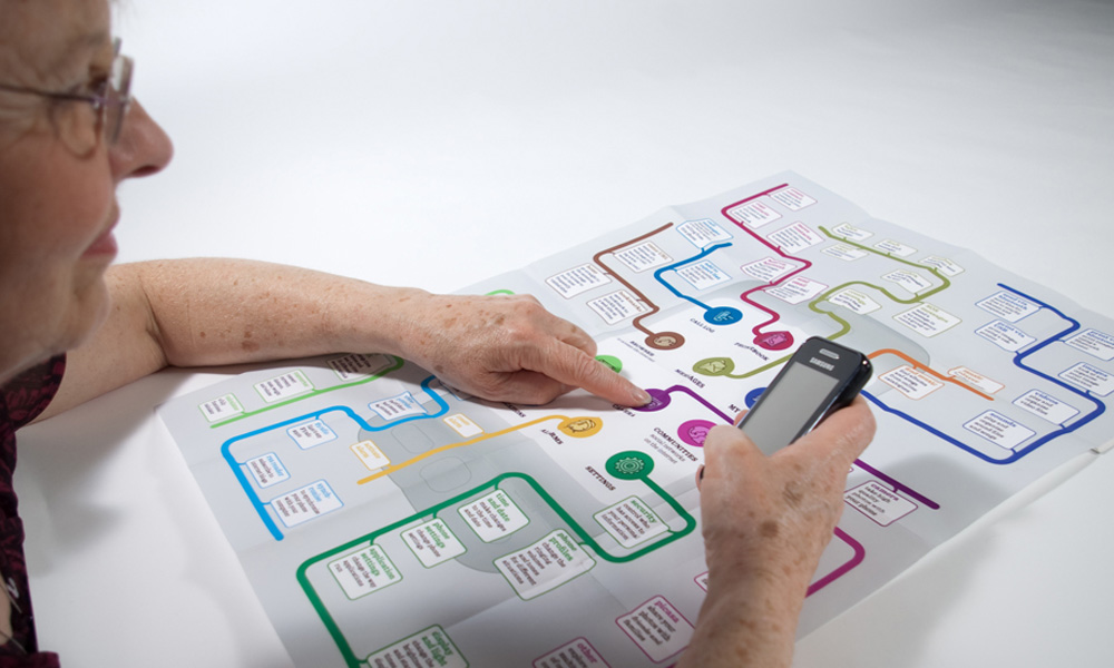 Photo of a person pointing at the map and holding a phone in hand